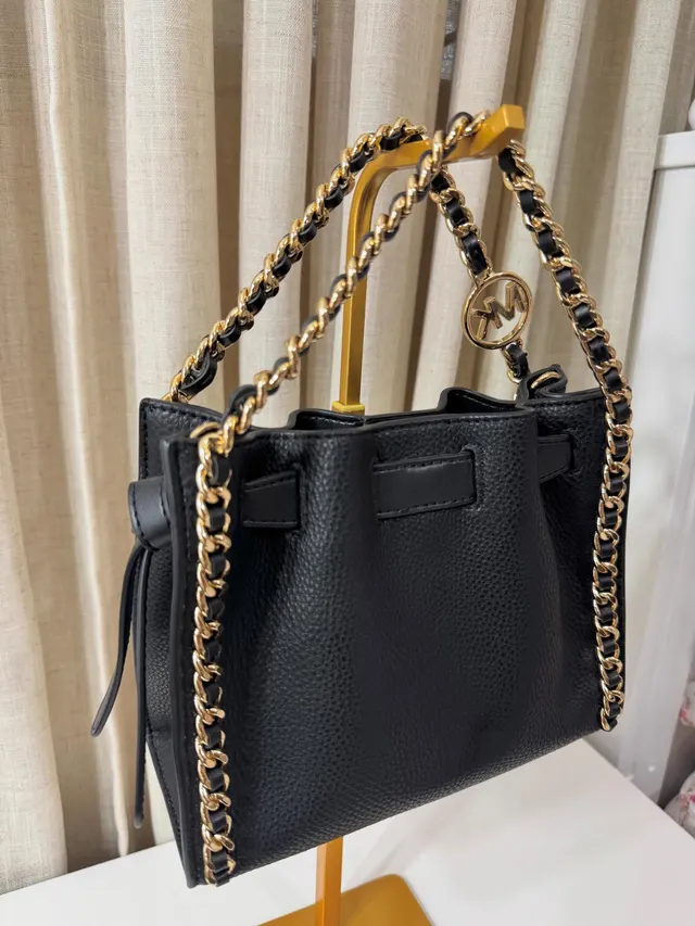 Bolso negro Michael Kors con cadena dorada visto desde un costado